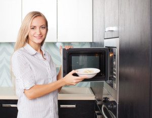 Woman warms up food in the microwave